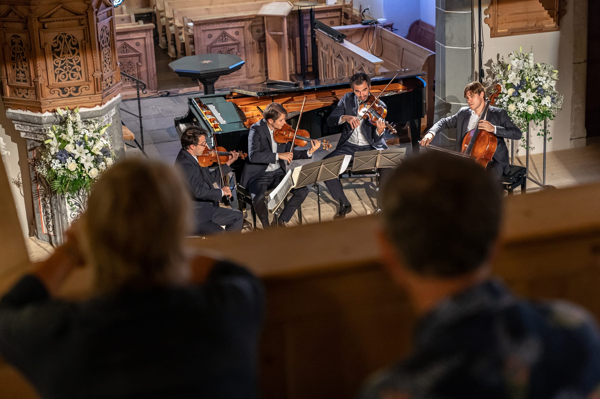 Eine Gruppe von Menschen beobachtet eine Gruppe von Musikern in einer Kirche.
