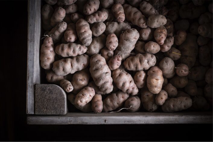 Kartoffeln in einer Holzkiste auf dunklem Hintergrund.
